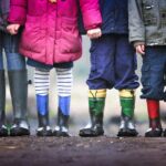 Vier Kinder spielen draußen auf einem sonnigen Spielplatz – Symbol für Kinderabsicherung, Vorsorge und eine sichere Zukunft.