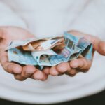 Geldscheine in den aufgebreiteten Händen – Symbol für vorteilhafte Änderungen beim Beitrag in der PKV.